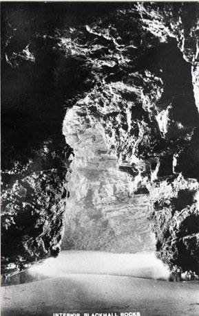 Postcard photograph entitled Interior Blackhall Rocks, showing what appears to be a cave-like structure illuminated from the left-hand side and water on the ground