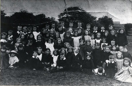 Photograph of a group of children, aged approximately from five to thirteen years, with a background of trees and grass; the children are described as children from Blackhall Rocks and appear to be on an outing to an unidentified place; there are approximately seventy children in the photograph and no adults can be seen; the photograph has a note on the back indicating that the children are from First School in Blackhall