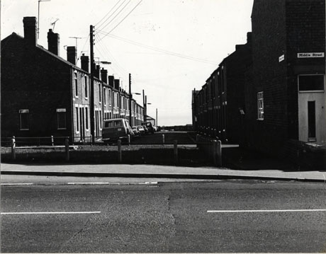 Photograph looking down Lower 10th Street taken from Middle Street, showing houses on either side of the street and vehicles parked in the street; the houses are typical houses of the latter part of the nineteenth century in a mining village and identified as being in Blackhall