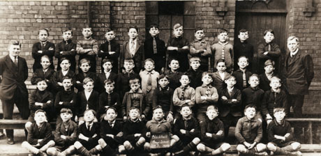 Photograph of the boys of Standard Five of Blackhall Boys' School, posed outside a brick building; the group consists of thirty seven boys, aged approximately ten years, and two men, presumably their teachers