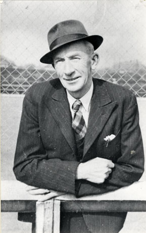 Photograph of the head and torso of Jack Carr, County Cricketer, and landlord of the Hardwick Hotel, Blackhall; he is leaning on a rail and is wearing a pin-striped suit with a tartan tie and Trilby hat; he appears to be middle-aged