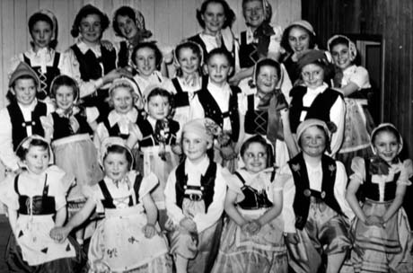 Photograph of twenty two children, aged between six and fifteen years, dressed as Tyrolean peasant girls and boys grouped against the wall of a room; they have been described as Children's Pantomime, Blackhall
