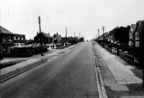 Photograph showing a road running away from the camera, with semi-detached houses on the right and a garage on the left, followed by houses; the photograph is indistinct and has been identified as BLackhall Coast Road