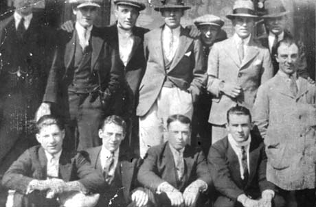 Photograph of eight young men standing in a row with four young men sitting in front of them; they are wearing suits and ties and seven of those standing are wearing hats; they have been described as a Group of Friends in Blackhall