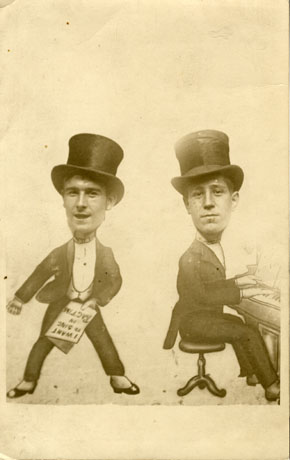 Photograph of a caricature of a man in evening dress holding a piece of paper with the words I Want to Sing in Ragtime written on it; next to that is another caricature of a man in evening dress playing the piano; the faces of two men, possibly identified as Cowley and Berriman, have been superimposed on the caricatures; they have been identified as having a connection with Blackhall