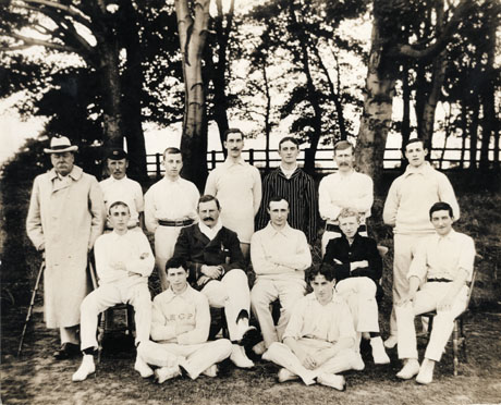 Group photograph of the fourteen members of a cricket team at Castle Eden, photographed in front of a group of trees;the group includes: second from the left on the back row, Mr. Judson, wicket keeper, brewery workman, and cricket groundsman;second from the left on the middle row, W. J. Nimmo, owner of the Castle Eden Brewery