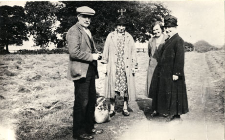 photograph of an elderly man, an elderly woman, a middle-aged woman and a young woman, standing on a path leading through a field in Castle Eden; they are wearing everyday clothes and a shopping bag is lying on the ground