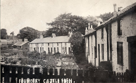 Photograph of the exterior of The Foundry, Castle Eden, showing the facades of The Foundry to the right and centre of the photograph, with other buildings in the distance and the gardens of The Foundry in the centre of the photograph