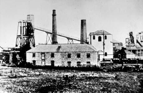 Photograph showing a low building in the centre, winding gear, two chimneys, winding house and other buildings in the distance of a colliery that has been identified as Castle Eden Colliery