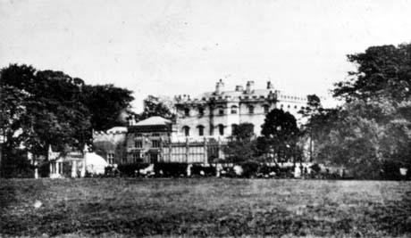 Photograph showing an indistinct image of the front of The Castle at Castle Eden, with the crenellation, glass houses and other outbuildings in a gothic style in view