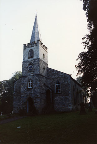 Photograph of the exterior of the west end of the church at Castle Eden, showing the tower and spire; the base of the tower is obscured by shadow