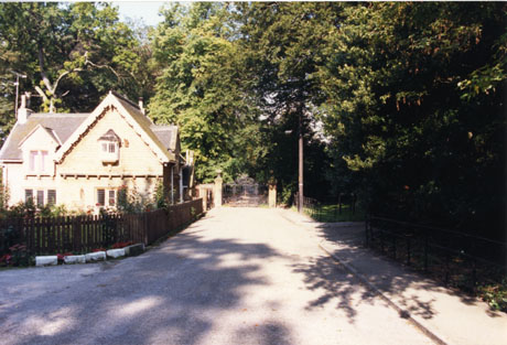 Photograph showing the exterior of the Lodge at Castle Eden, with trees on the right-hand side and gates into the park in the distance