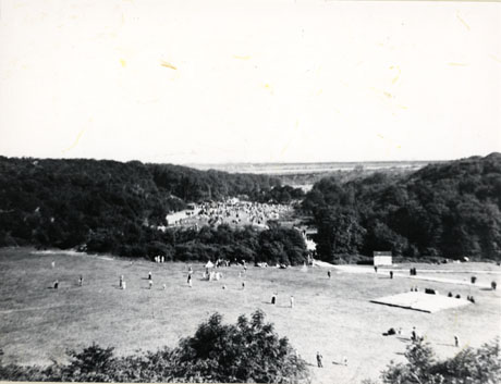 Photograph of Crimdon Dene, showing in the foreground a playing field, in the middle distance, a bank of trees and, beyond them, a crowded beach