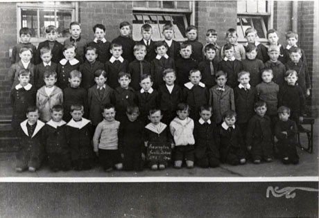 Photograph of a group of forty nine boys aged approximately eight years, posed in front of a brick- built building; a child on the front row holds a notice reading: Easington Junior School Std. 2 1919