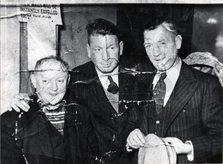 Photograph of a close-up of the head and torso of three men wearing suits and standing in an unidentified club; the men are identified as Mr. Marr, Mr. Williams, and friend