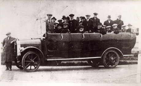 Photograph of a charabanc taken from the side showing twenty two men in the charabanc and a man leaning on its bonnet; the photograph is identified as being in Easington Colliery