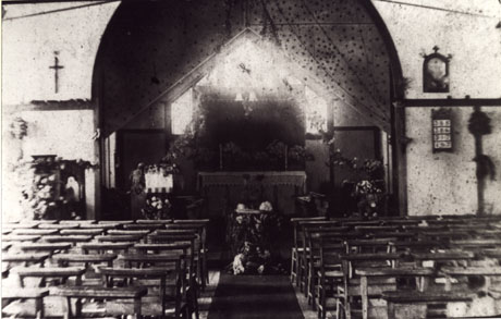 Photograph of the interior of the Church of The Ascension, looking towards the altar showing the church decorated for the Harvest Festival; the chairs in the body of the church may be seen as may the pulpit and lectern