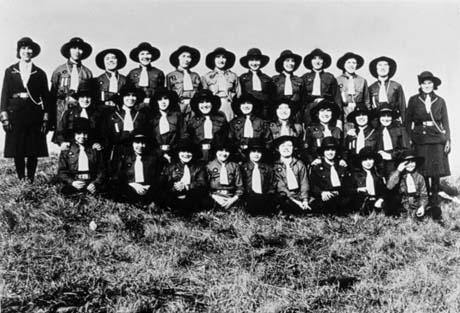 Photograph of twenty six Girl Guides posed in three rows on grass; they are accompanied by two Guiders; their uniform includes a hat with a brim; they have been identified as Easington Colliery Girl Guides
