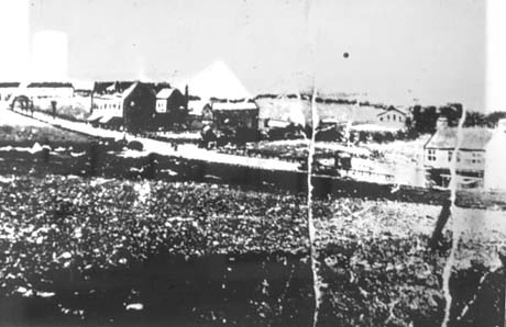 Photograph showing a road running across the picture with houses on the right and open fields on the left; it is indistinct and has been identified as Seaside Lane, Easington Colliery