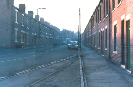 Photograph of a street, with terraced houses on both sides, running away from the camera; a car is parked on the right and another car is travelling away from the camera on the left; the street has been identified as Ascot Street, Easington Colliery