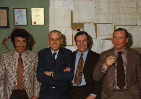Photograph showing four men standing in a row in front of a notice board and a wall bearing framed certificates; the men are wearing collars, ties and jackets, and have been identified as, from Left to Right: Councillor McWilliams, Durham County Council; Harold Todd, Safety Officer, Durham County Council; Jim Hughes, Safety Officer, Durham County Council; Ron Brewis, Safety Officer, Durham County Council. The photograph was taken on the occasion of the retirement of Harold Todd, who, at the request of Jim Hughes, wrote a letter to Jim Hughes describing his, Harold Todd's, experience as a member of the Blackhall Colliery Rescue Brigade at the disaster in the pit at Easington in May 1951, which may be read below