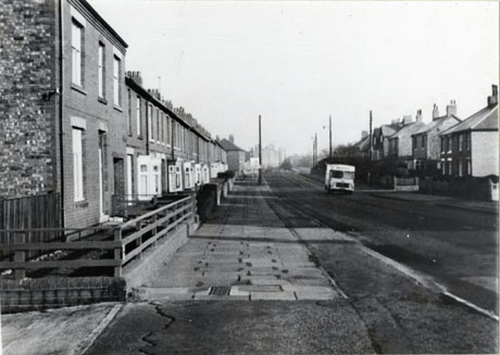 Photograph looking along a road lined with terraced houses on the left=hand side and larger, possibly detached, houses on the right-hand side; a motor van is parked facing the camera on the right- hand side of the road; the road is described as Thorpe Road, Easington Village