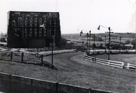 Photograph showing the scoreboard, and course of the track curving round to the right, of Riddels Dog Track, Easington Village; behind the track and scoreboard can be seen fields stretching to the horizon; the track was opened in 1935 and was owned by Frankie Franks and later by Riddel
