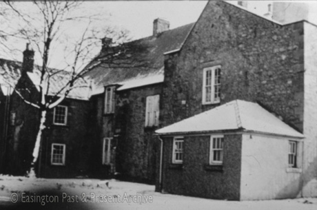 Photograph of the rear of a large house under snow; it has been identified as The Old Presbytery in Easington Village