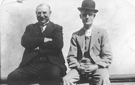 Photograph of a middle-aged man dressed in a dark suit and a wing collar sitting next to a man dressed in a lighter coloured suit and a bowler hat; they have been identified as Mr. Fewster and Mr. Tate, the Co-Op Horse Keepers