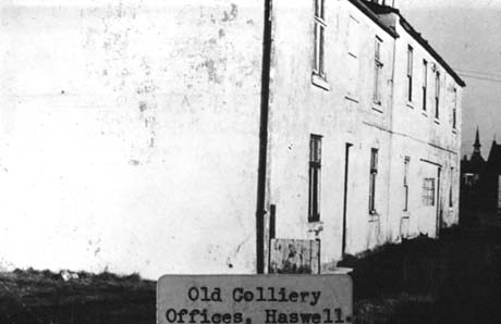 Photograph with a typed note on it as follows: Old Colliery Offices. Haswell, showing the side and front of a plain building, with stucco on it, attached to another similar building with a porch; the buildings have three windows on the first floor and two and a doorway on the ground floor This photograph was submitted by Philip Soakell from the album 'History of Haswell and District', which was compiled by his grandfather Fred Soakell.