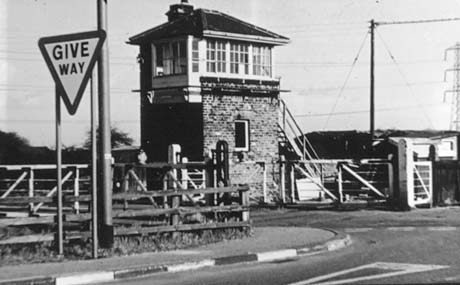 Photograph showing the side of a signal box surrounded by the gates of the level crossing; a Give Way sign can be seen on a road approaching the level crossing, which has been identified as Thornley Crossing, Haswell