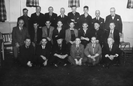 Photograph showing twenty two men posed in three rows in a room with the same decor as the canteen in 100; seventeen of the men are wearing suits and ties and the rest overalls; they have been identified as being recipients of I. C. I. Safe Driving Awards in Haswell
