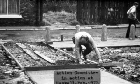 Photograph bearing a typed note reading: Action Committee in action at Haswell. Feb. 1972, showing a road running across the photograph with the base of houses on one side and bollards on the other; in front of the bollards, a man is crouched with a piece of wood across a path leading from the road, between rough ground; a smooth concrete surface is in front of the wood and a rough surface is behind; it is likely that he is engaged in the concreting of a path; the photograph has further been described as Tidying Up The Village This photograph was submitted by Philip Soakell from the album 'History of Haswell and District', which was compiled by his grandfather Fred Soakell.