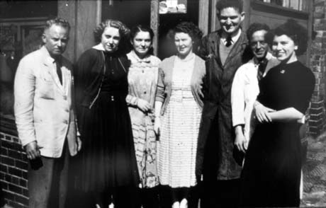 Photograph of four women and three men standing outside what may be a shop, although no details of the premises can be seen; one man is dressed in dark a dark overall and two men in a light overall jacket; the women are dressed in ordinary dresses; they have been identified as employees of Sherburn Hill Co-operative Society