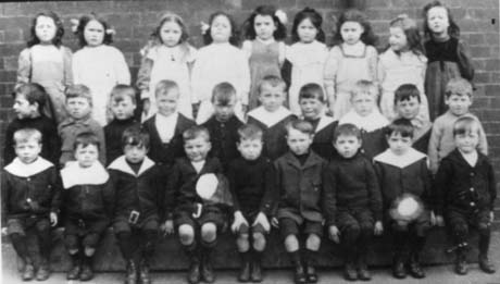 Photograph of twenty eight children, aged approximately six years, posed against a brick wall; they have been identified as pupils at an infants' school in Haswell
