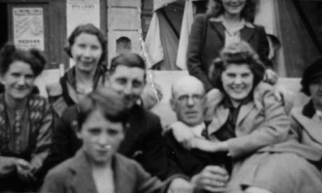 Photograph of the head and shoulders of a woman on the left of the photograph dressed in a patterned garment ;next to her are the head and shoulders of a woman in a coat, in front of whom are the head and shoulders of a man and a boy; next to them are the head and shoulders of a bald man; a woman wearing a jacket and skirt has her arms round his neck; behind her part of the torso of another woman can be seen; they have been identified as Mr. and Mrs. Belton; Mrs. Cummings; Mrs. Nellie Scott; Bobby Cummings; Mr. Young; of Haswell