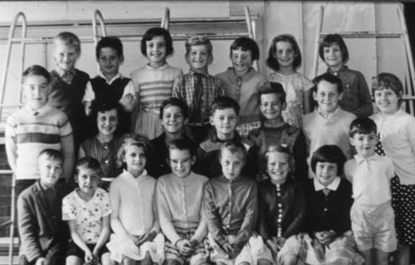 Photograph of twenty two children, aged between approximately five and seven years, posed in a room with tiles on the wall and with ladder-like equipment behind them; the children have been identified as being in Haswell