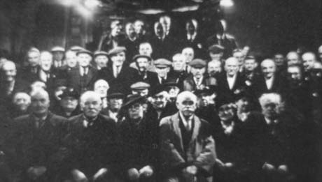 Photograph showing approximately forty elderly people, described as Old Age Pensioners sitting in five rows with eight standing at the back of the group; they are wearing suits and caps and coats and hats and are looking towards the camera; the occasion has not been specified; the name Thomas H. Errington has been given, but the individual to whom it applies has not been identified