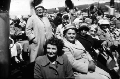Photograph of approximately thirty women in overcoats and hats sitting on the deck of a boat with hills in the distance; they have been identified as members of Haswell Women's Institute on an outing to Loch Lomond