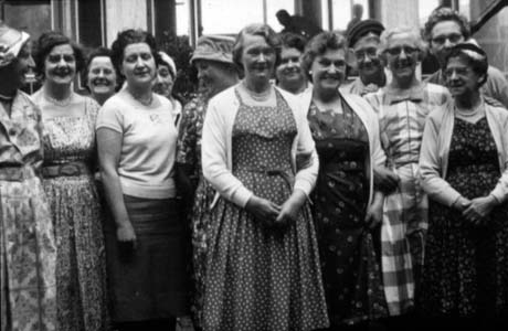Photograph of a group of thirteen women wearing summer frocks standing in an unidentified location; they have been described as members of Haswell Women's Institute on a trip to Holland