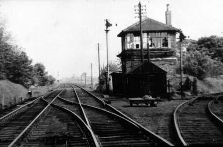 Photograph showing a railway line running away from the camera into the distance, past a signal box on the right of the picture; also on the right, another line branches off; there are bushes on the left of the line and open country on the right, past the signal box; the photograph has been identified as Pesspool Junction, Haswell