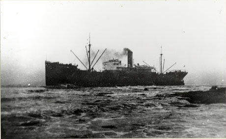 Photograph of a ship in the middle distance with sea in the foreground; the ship has a funnel from which smoke is issuing and appears to be on an even keel; the photograph has been identified as The West Hika aground at Hawthorn, 15 January 1936