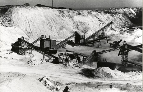 Photograph showing the interior of Hawthorn Magnesian Limestone Quarry, with the walls and floor of the quarry and what appear to be chutes and buildings; in the foreground a large motor vehicle can be seen, possibly collecting the limestone