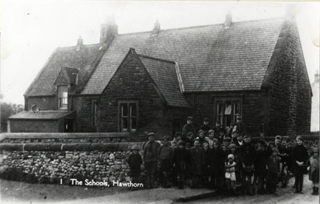 Postcard photograph entitled The Schools, Hawthorn, showing the exterior of the school behind a wall; in front of the wall a group of approximately thirty children with a pony and cart can be seen