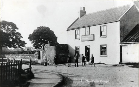 Postcard photograph entitled 3 Hawthorn Village, showing the exterior of the Stapylton Arms public house in Hawthorn and the road in front of it; five boys and one girl can be seen indistinctly on the road in front of the public house; the indistinct figure of a woman and a small girl can be seen at the door of the building