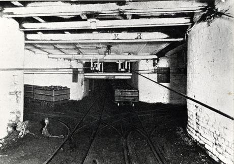 Photograph showing the junction of four roadways underground at Horden Colliery; the walls and ceiling are painted in a light colour and rails can be seen on the floor; one tub is in the left hand roadway and another is in the roadway in front of the camera