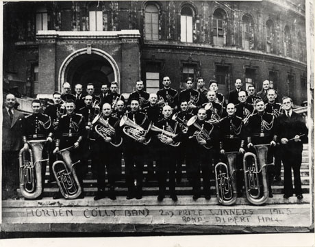 Photograph of thirty three members of the Horden Colliery Band posed outside the Royal Albert Hall, London; the members of the band are in uniform and holding their instruments; under the photograph the following has been written: Horden Colly. Band 2nd Prize Winners 1945 Royal Albert Hall