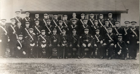 Photograph of thirty five members of the Saint John Ambulance Brigade, all but two in uniform, posed outside a hut identified as being in Horden