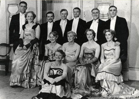 Photograph of twelve members of the cast of Bittersweet by Noel Coward, performed by the Horden Operatic Society, posed against the scenery of the production; the six men are wearing white tie and the six women evening dresses