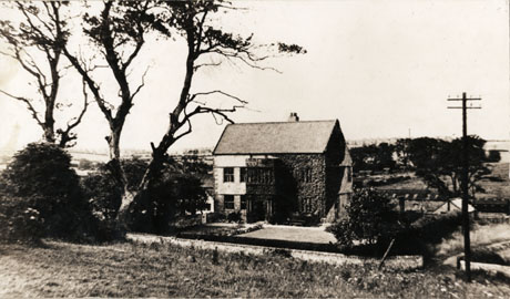 Photograph of the exterior of the front of Horden Hall; the Hall can be seen in the middle distance with a road running in front of the building and outbuildings to its left; the Hall has creeper on the left of its facade